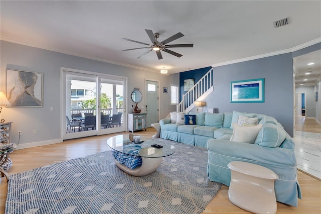 living room with light wood-style flooring, baseboards, visible vents, a ceiling fan, and ornamental molding