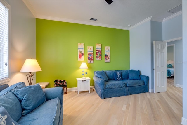living room featuring light wood-style floors, visible vents, baseboards, and ornamental molding