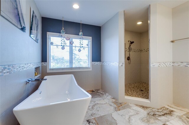 full bath featuring a sink, a freestanding tub, tile walls, marble finish floor, and tiled shower