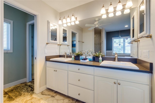 bathroom featuring a ceiling fan, marble finish floor, a sink, and double vanity