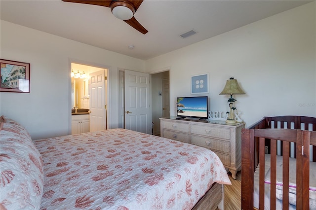 bedroom with a ceiling fan, wood finished floors, visible vents, and ensuite bathroom