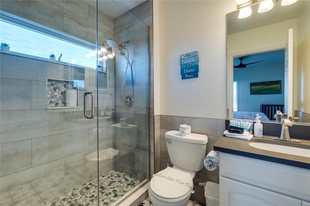 full bath with a shower stall, toilet, vanity, and tile walls