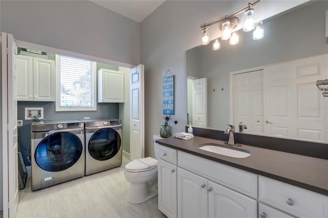 bathroom with washing machine and clothes dryer, toilet, and vanity