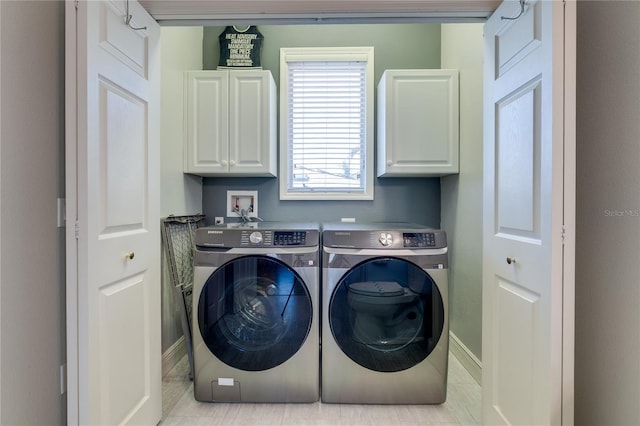 clothes washing area featuring separate washer and dryer, baseboards, and cabinet space