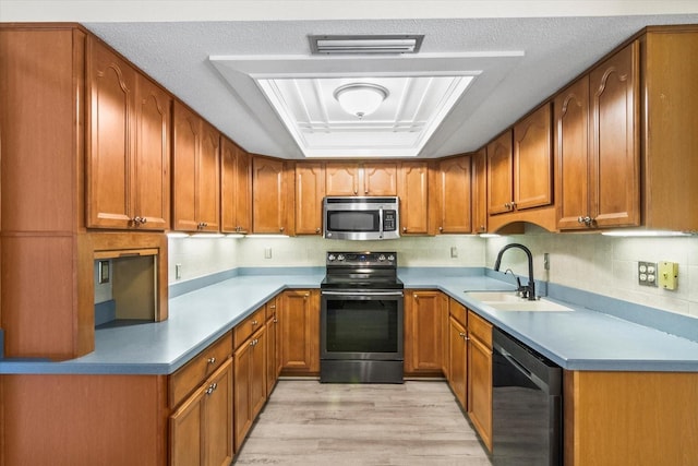 2961 Valencia Rd, Venice, FL 34293 - kitchen with visible vents, brown cabinetry, a sink, light wood-style flooring, and appliances with stainless steel finishes