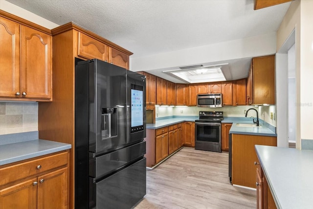 2961 Valencia Rd, Venice, FL 34293 - kitchen featuring brown cabinetry, appliances with stainless steel finishes, light wood-style flooring, and a sink
