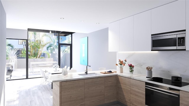 2170 Robinhood St Unit A1-304, Sarasota, FL 34231 - kitchen featuring stainless steel microwave, modern cabinets, oven, a peninsula, and expansive windows