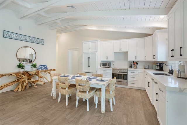 305 73rd St, Holmes Beach, FL 34217 - kitchen with light wood-type flooring, appliances with stainless steel finishes, lofted ceiling with beams, and a sink