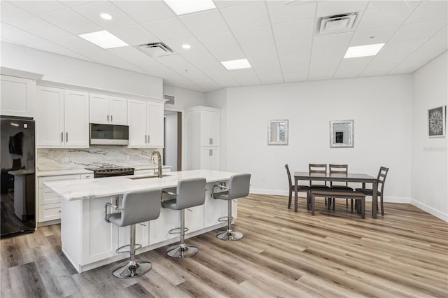 516 Tamiami Trl S Unit 102, Nokomis, FL 34275 - kitchen featuring freestanding refrigerator, a sink, a kitchen breakfast bar, white cabinetry, and decorative backsplash