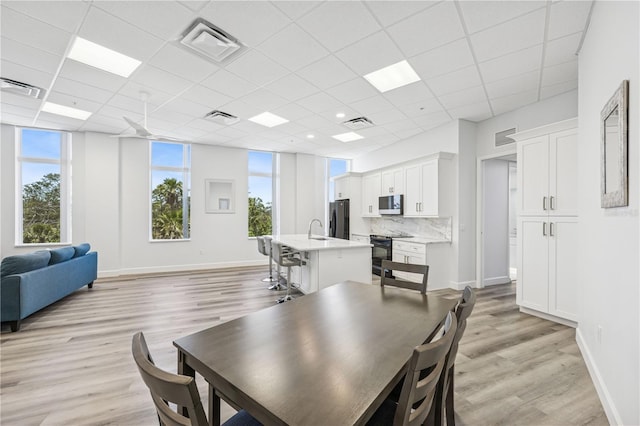 516 Tamiami Trl S Unit 102, Nokomis, FL 34275 - dining room with light wood-style floors, a paneled ceiling, and baseboards
