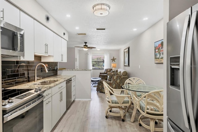 4169 66th Street Cir W Unit 4169, Bradenton, FL 34209 - kitchen with appliances with stainless steel finishes, a sink, decorative backsplash, a ceiling fan, and white cabinets