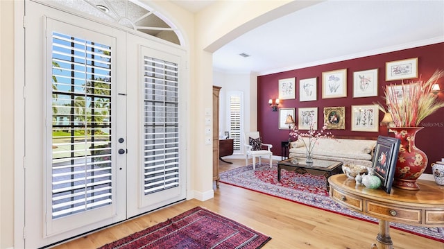 entryway with crown molding, arched walkways, wood finished floors, and visible vents