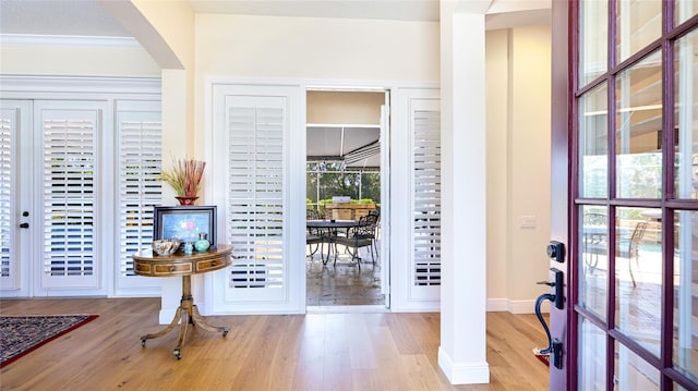 foyer with crown molding, baseboards, arched walkways, and wood finished floors