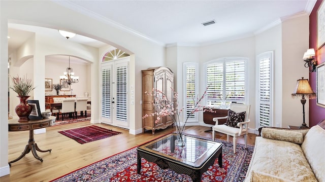 living area featuring arched walkways, a notable chandelier, wood finished floors, and visible vents
