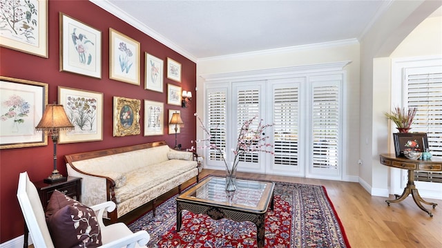living area with baseboards, ornamental molding, and wood finished floors