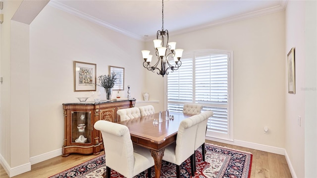 dining area with baseboards, ornamental molding, light wood-style flooring, and a chandelier