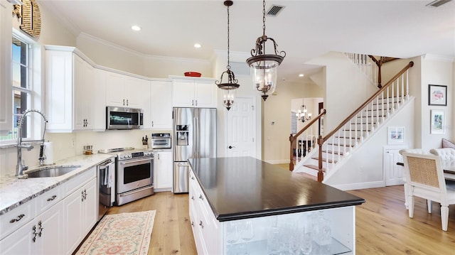 kitchen featuring crown molding, a sink, appliances with stainless steel finishes, and a kitchen island