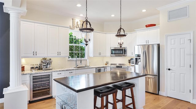 kitchen with visible vents, decorative columns, wine cooler, a sink, and appliances with stainless steel finishes