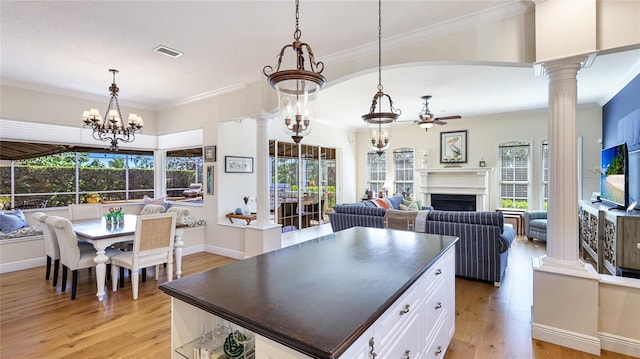 kitchen with open floor plan, dark countertops, light wood finished floors, and ceiling fan with notable chandelier