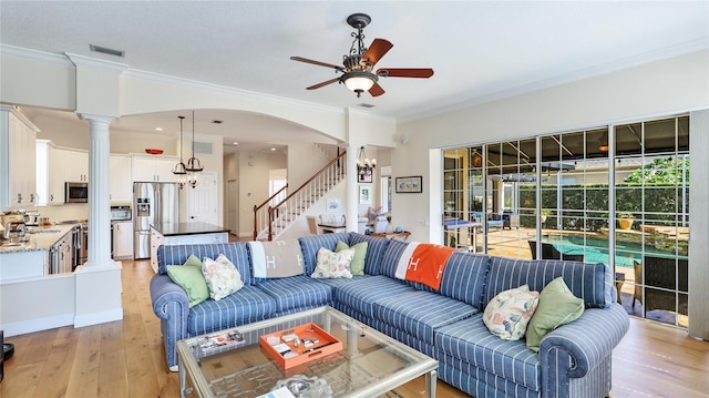 living room featuring ceiling fan, decorative columns, visible vents, and light wood-style floors