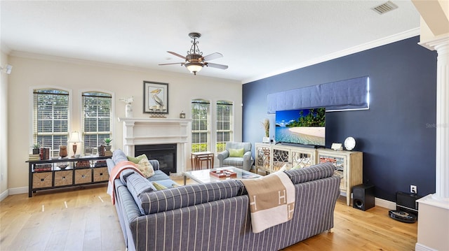 living room with crown molding, ceiling fan, wood finished floors, and visible vents