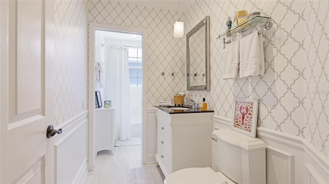 bathroom with vanity, toilet, and wallpapered walls