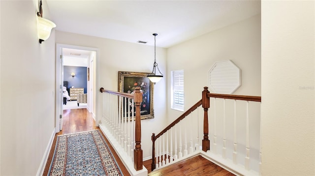 corridor featuring visible vents, wood finished floors, and an upstairs landing