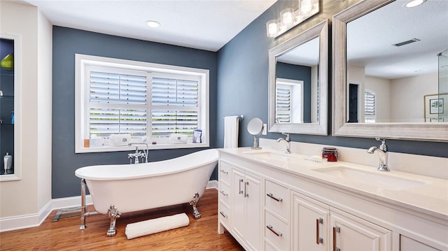 bathroom featuring visible vents, a sink, wood finished floors, and a wealth of natural light