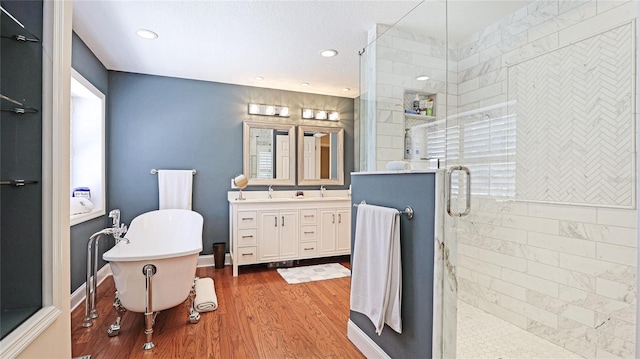 full bath with a freestanding bath, vanity, recessed lighting, wood finished floors, and a stall shower