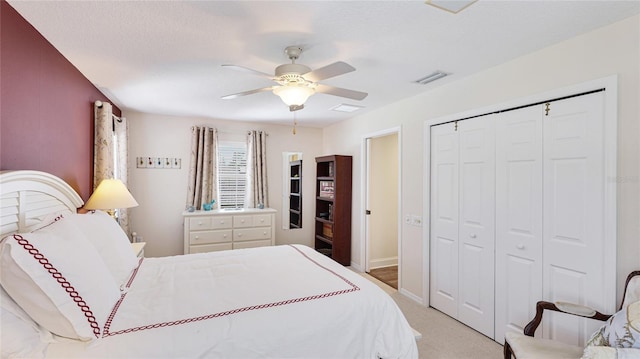 bedroom featuring a ceiling fan, visible vents, baseboards, a closet, and light carpet