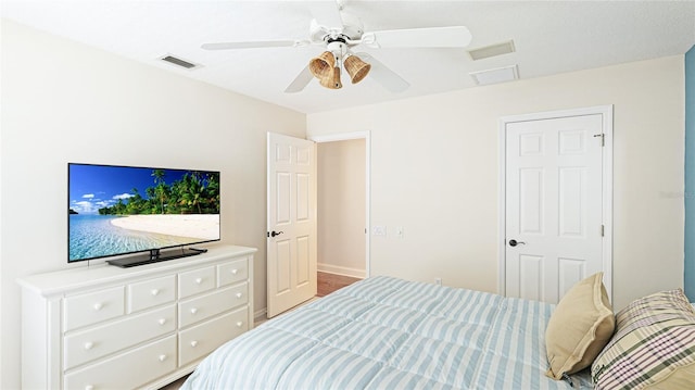 bedroom featuring baseboards, ceiling fan, wood finished floors, and visible vents