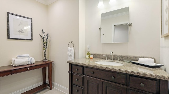 bathroom featuring baseboards, ornamental molding, and vanity