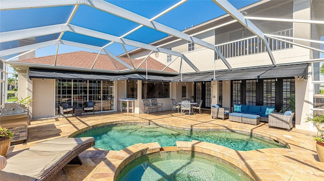 view of swimming pool featuring outdoor lounge area, a patio, exterior kitchen, glass enclosure, and a pool with connected hot tub