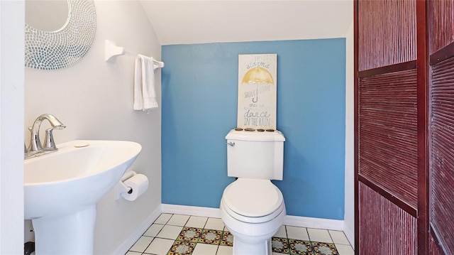 bathroom with a sink, tile patterned flooring, toilet, baseboards, and vaulted ceiling