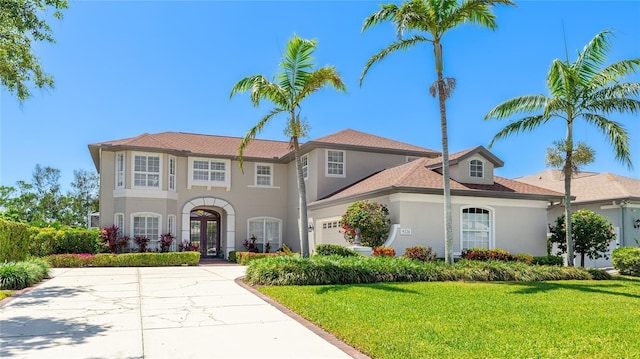 mediterranean / spanish home featuring a garage, french doors, a front yard, and stucco siding