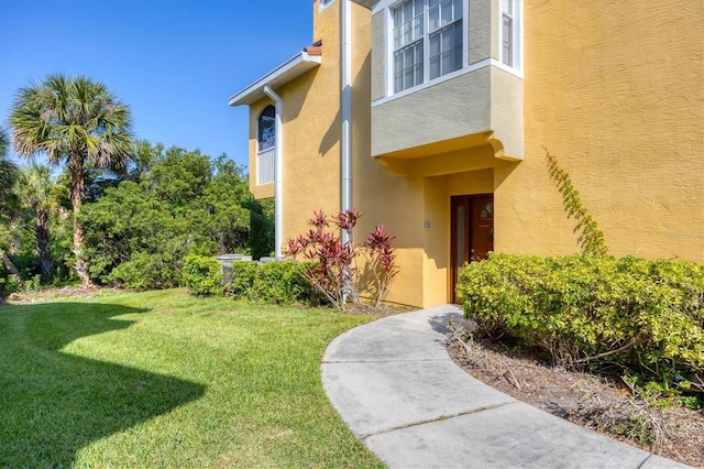 property entrance featuring stucco siding and a yard