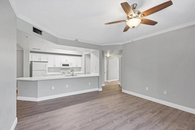 unfurnished living room featuring a sink, wood finished floors, ceiling fan, and ornamental molding