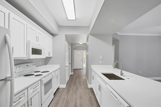 kitchen featuring white appliances, a sink, light countertops, light wood-style flooring, and white cabinets