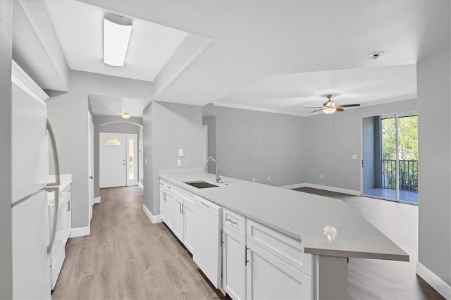 kitchen featuring white appliances, a sink, a peninsula, white cabinets, and baseboards