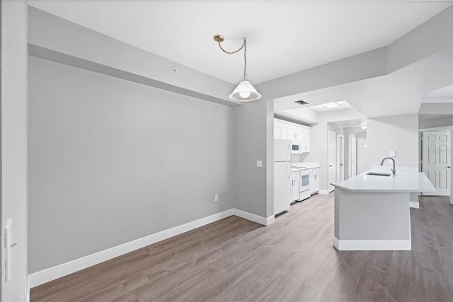 kitchen featuring white appliances, wood finished floors, white cabinets, and light countertops