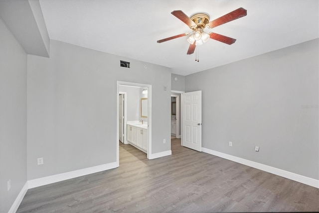 unfurnished bedroom featuring wood finished floors, baseboards, and ensuite bath