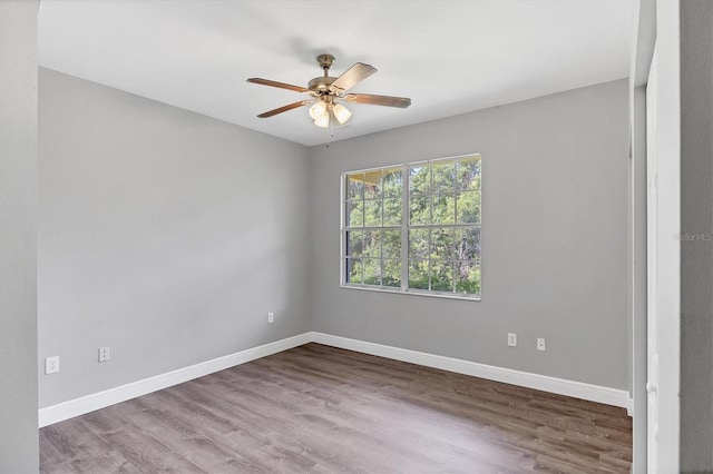 spare room with wood finished floors, a ceiling fan, and baseboards