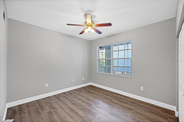 spare room with wood finished floors, a ceiling fan, and baseboards