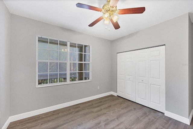 unfurnished bedroom with wood finished floors, baseboards, a closet, and ceiling fan