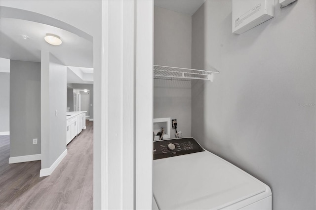 clothes washing area featuring washer / dryer, light wood-style floors, baseboards, and arched walkways