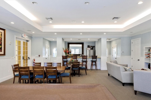 dining room featuring a raised ceiling, carpet floors, wainscoting, recessed lighting, and a decorative wall