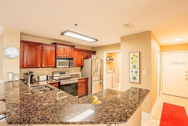 4061 Crockers Lake Blvd Unit 2618, Sarasota, FL 34238 - kitchen with washing machine and clothes dryer, a sink, a peninsula, appliances with stainless steel finishes, and visible vents
