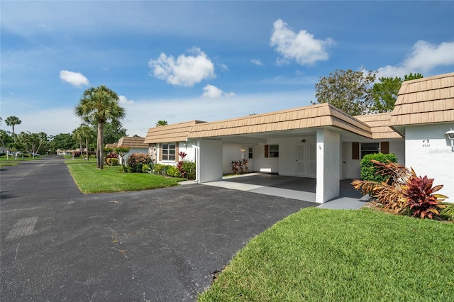 5521 Riverbluff Cir Unit V-10, Sarasota, FL 34231 - view of front facade featuring asphalt driveway, mansard roof, stucco siding, a front lawn, and an attached carport
