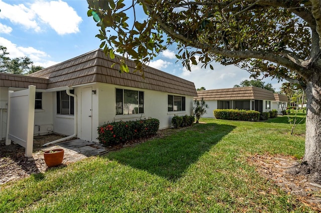5521 Riverbluff Cir Unit V-10, Sarasota, FL 34231 - view of property exterior with mansard roof, a yard, and stucco siding