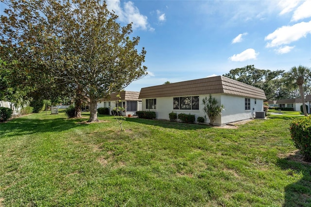 5521 Riverbluff Cir Unit V-10, Sarasota, FL 34231 - rear view of property featuring a yard, mansard roof, central AC unit, and stucco siding
